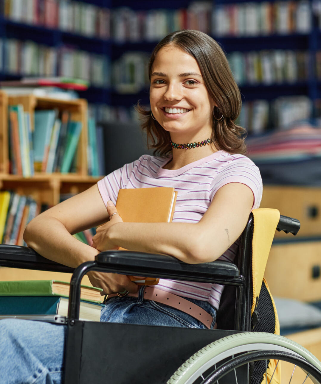 Happy teenage girl in wheelchair at the library